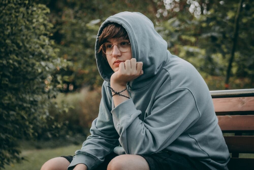 Young mans Portrait in Hooded Clothing with a Sad Expression. Grieving man wears hooded clothing, displaying sadness and sorrow.